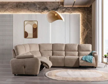 A detailed view of the Atlas Recliner Köşe Takımı, a contemporary L-shaped corner sectional sofa upholstered in textured beige fabric. The image shows its modern design with sleek lines and wide seats. The central console unit is featured, with an open lid, integrated cup holders, and a built-in Bluetooth speaker system visible on the side. The sofa is placed in a premium living room with light wood floors and textured wall paneling with LED backlighting.