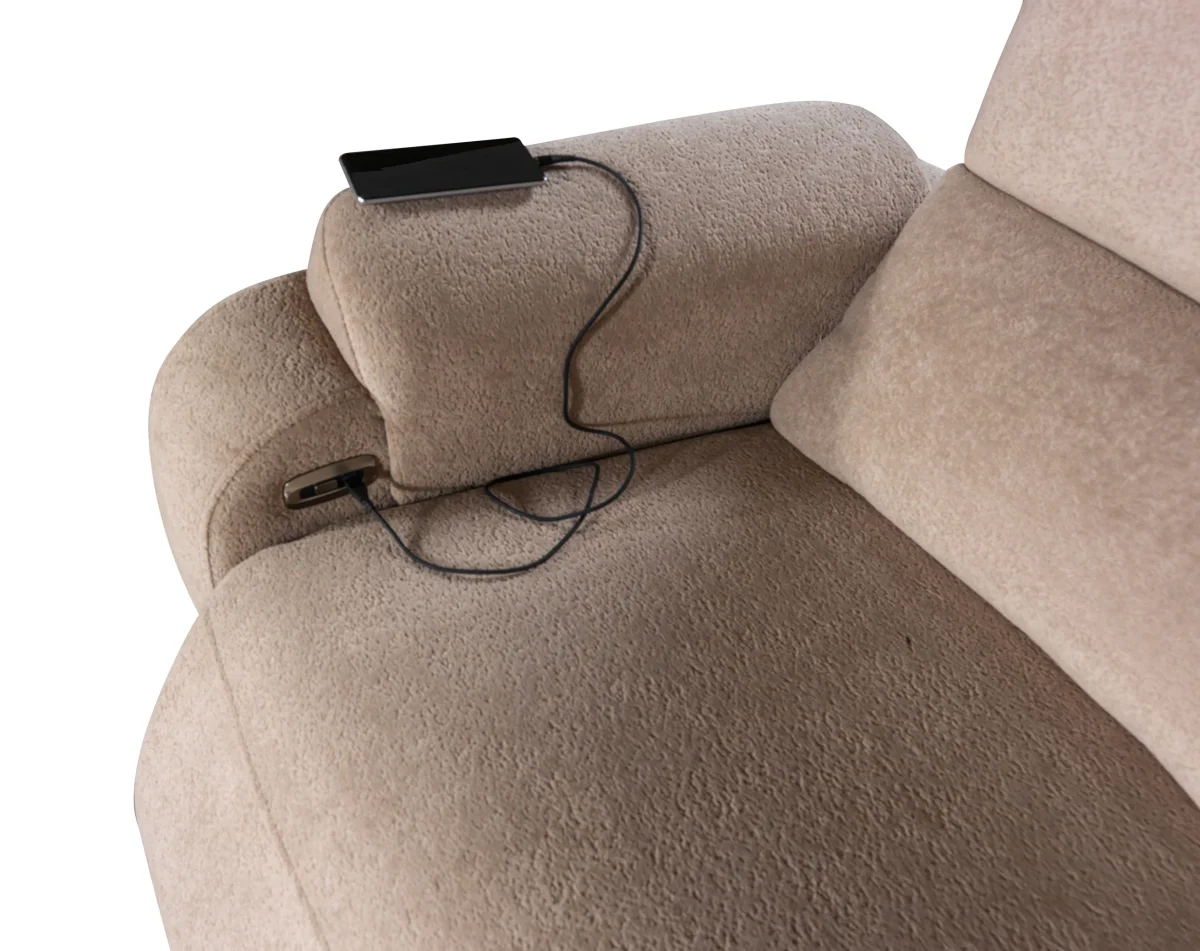 A detailed view of the Atlas Recliner Köşe Takımı, a contemporary L-shaped corner sectional sofa upholstered in textured beige fabric. The image shows its modern design with sleek lines and wide seats. The central console unit is featured, with an open lid, integrated cup holders, and a built-in Bluetooth speaker system visible on the side. The sofa is placed in a premium living room with light wood floors and textured wall paneling with LED backlighting.