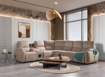 A detailed view of the Atlas Recliner Köşe Takımı, a contemporary L-shaped corner sectional sofa upholstered in textured beige fabric. The image shows its modern design with sleek lines and wide seats. The central console unit is featured, with an open lid, integrated cup holders, and a built-in Bluetooth speaker system visible on the side. The sofa is placed in a premium living room with light wood floors and textured wall paneling with LED backlighting.