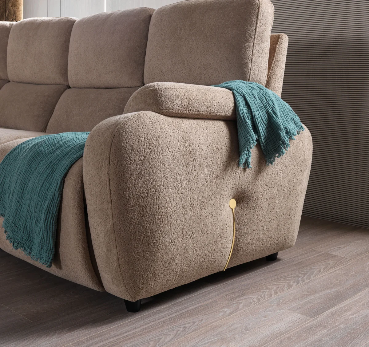 A detailed view of the Atlas Recliner Köşe Takımı, a contemporary L-shaped corner sectional sofa upholstered in textured beige fabric. The image shows its modern design with sleek lines and wide seats. The central console unit is featured, with an open lid, integrated cup holders, and a built-in Bluetooth speaker system visible on the side. The sofa is placed in a premium living room with light wood floors and textured wall paneling with LED backlighting.
