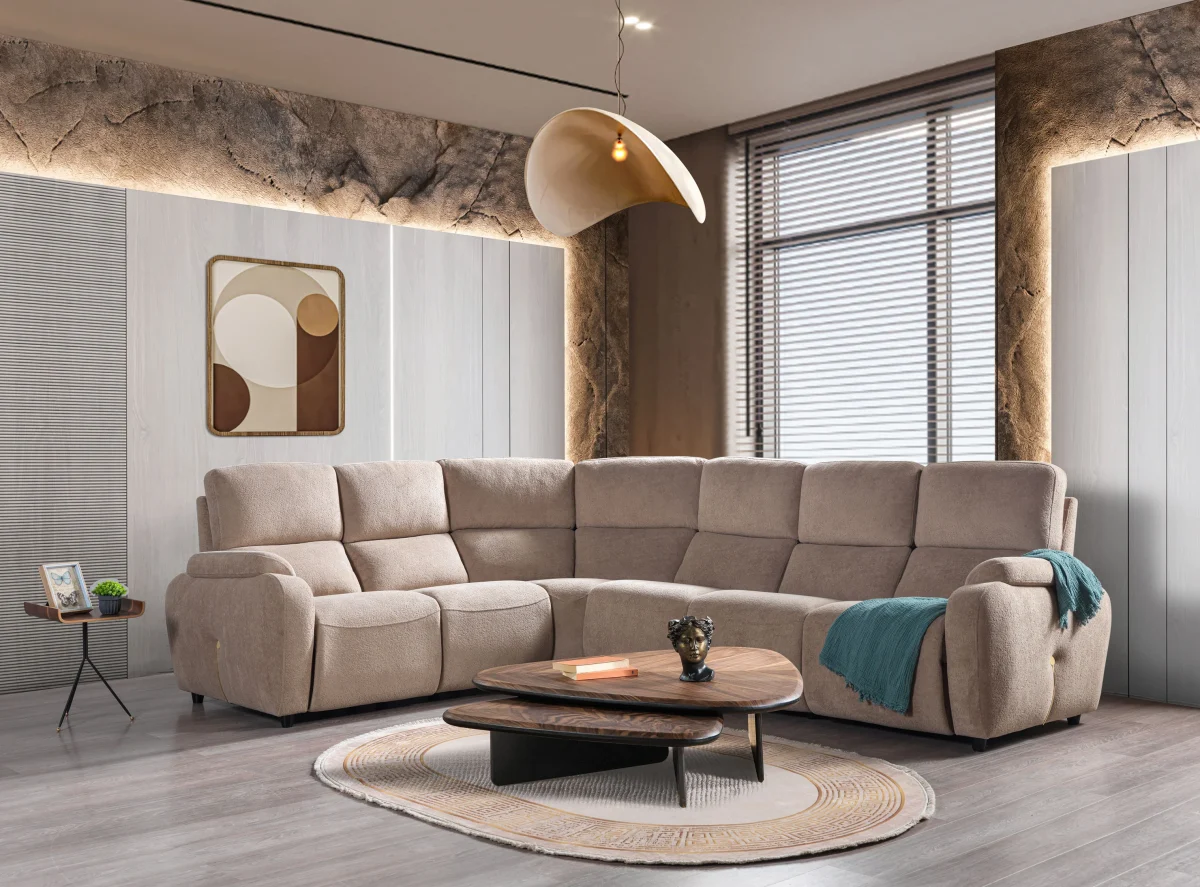 A detailed view of the Atlas Recliner Köşe Takımı, a contemporary L-shaped corner sectional sofa upholstered in textured beige fabric. The image shows its modern design with sleek lines and wide seats. The central console unit is featured, with an open lid, integrated cup holders, and a built-in Bluetooth speaker system visible on the side. The sofa is placed in a premium living room with light wood floors and textured wall paneling with LED backlighting.